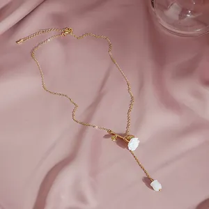 Close-up of golden rose pendant necklace with white flower bud on pink satin