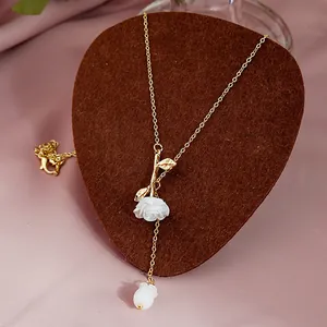 Detail of rose pendant necklace with white flower and gold leaves on a velvet background