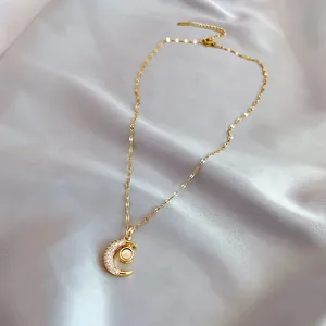 Detail of golden crescent moon necklace with sparkling crystals and opal pendant