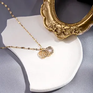 Macro shot of gold shell pendant with pearls and rhinestones on a white textured stone