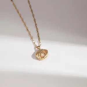 Detail of a gold hollow shell pendant with a white pearl on a flat snake chain