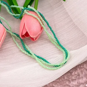 Detailed macro view of 2-4mm faceted green glass beads on layered necklace