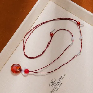 Detailed view of handmade necklace with red translucent ring and crescent moon pendant