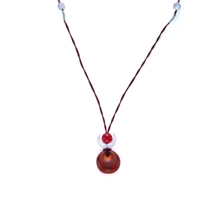 Detailed view of red agate pendant necklace with a white crescent and crimson cord