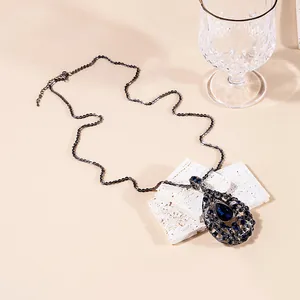 Macro view of long vintage necklace with blue pear-shaped crystal and filigree pendant