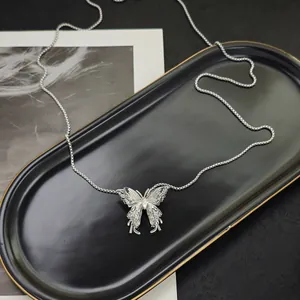Detailed view of silver hollow butterfly pendant necklace on a matte black jewelry tray