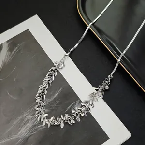Close-up of silver snake chain with leaf pendants on artistic background display