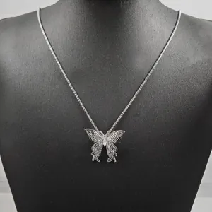 Close-up of a silver hollow butterfly pendant with a classic box chain on a black bust
