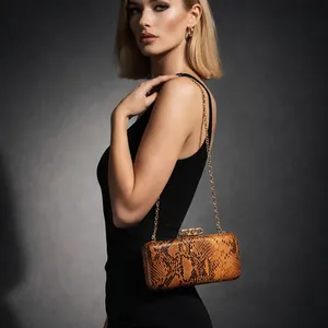Detail of snake print clutch bag with gold chain strap and metal clasp on grey background