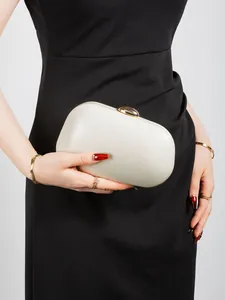 Detail showing pearl white capsule hard shell clutch with golden metallic pebble clasp