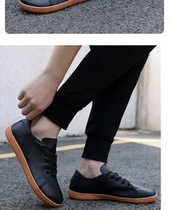 Detail von atmungsaktiven schwarzen Barfußschuhen mit Gummisohle auf Asphaltbelag