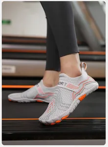 Detail of gray breathable mesh water shoes with orange anti-slip sole on a treadmill