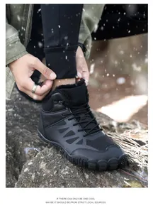 Detail view of black high-top outdoor snow boots with warm faux fur lining on rocks