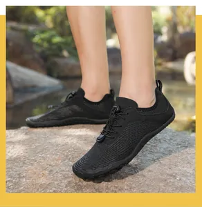 Close-up of black quick-dry water shoes with honeycomb mesh on outdoor river rocks