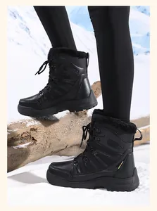 Outdoor close-up of waterproof black leather snow boots with warm fur lining on snow