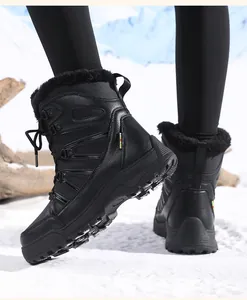 Close-up of black snow boots with thick faux fur lining and non-slip rubber soles in snow