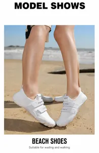 Zapatos de agua blancos transpirables con velcro mostrados en una playa de arena