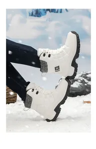 White high-top snow boots with knit collar and thick non-slip soles in a snowy landscape