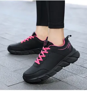 Dettaglio di scarpe sportive in pelle sintetica nera con lacci rosa e suola antiscivolo