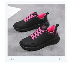 Dettaglio di sneakers in pelle sintetica nera con lacci rosa e scritte logo di tendenza