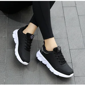 Dettaglio di scarpe sportive in pelle nera da donna con suola bianca spessa e antiscivolo