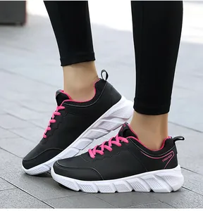 Dettaglio delle sneakers sportive da donna in pelle nera con lacci rosa e suola spessa