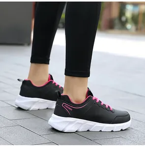 Sneakers in ecopelle nero e rosa con spessa suola bianca indossate all'aperto da una donna