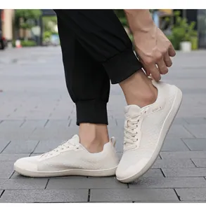 Nahaufnahme des atmungsaktiven Mesh-Gewebes und SPORT IS Text auf beigen Barfußschuhen