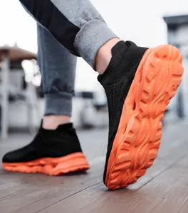 Detail showing the thick orange wavy sole and black knitted upper of a casual sneaker