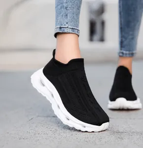 Close-up of black breathable knit sneakers with wavy white platform soles on model