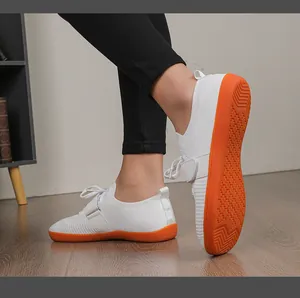 Close-up of lightweight gym shoes with orange anti-slip rubber soles on wooden floor
