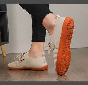 Close-up of beige knit fitness shoe with orange non-slip rubber sole on wooden floor