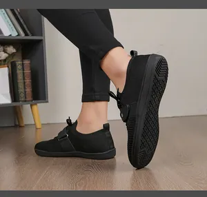 Close-up of black breathable knit fitness shoes with non-slip rubber soles on wood floor
