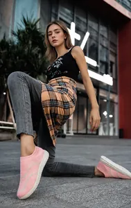 Close-up of pink breathable knitted slip-on walking shoe on model during street walk