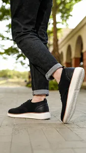Nahaufnahme der schwarzen Strick-Oxfords mit Brogue-Details und dicker weißer Sohle