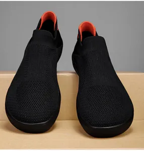 Close-up of black mesh knit walking shoe with orange lining on cardboard box