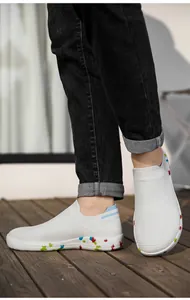 Detail of white knit slip-on sneakers with colorful patterned soles on a wooden deck