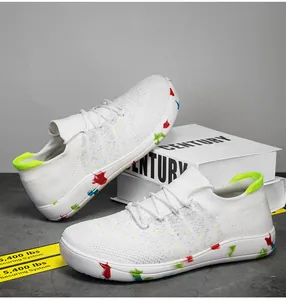 Detail view of white breathable mesh sneaker with colorful paint splatter sole and green pull tab