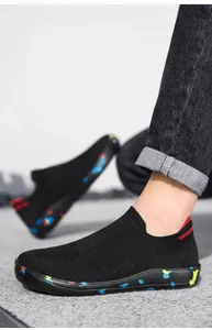 Close-up of black knit slip-on sneakers with colorful graffiti pattern on the rubber sole