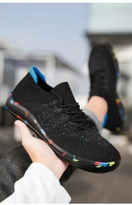 Detail of breathable black knitted sneaker with vibrant paint splatter sole and blue heel tab