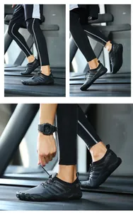 Dettaglio di scarpe da fitness a piedi nudi nere traspiranti con lacci elastici in palestra