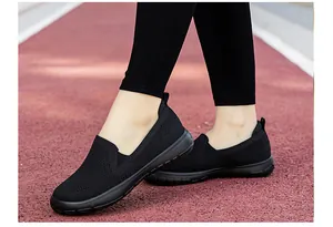 Detalle de zapatos de punto negro transpirable con suela acolchada en pista roja