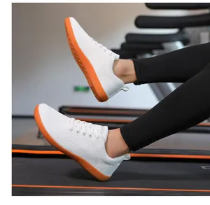 Nahaufnahme weißer Barfußschuhe aus Strick mit orangefarbener Sohle auf dem Laufband