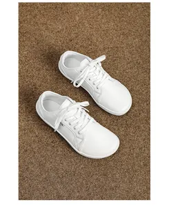 Dettaglio macro di sneakers a piedi nudi in pelle bianca con etichetta su tappeto