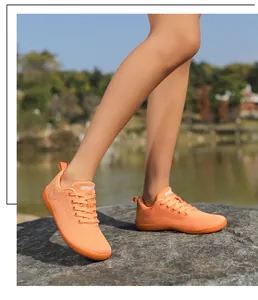 Detailansicht orangefarbener Barfußschuh aus Mesh mit SPORT-Label auf einem Felsen im Freien