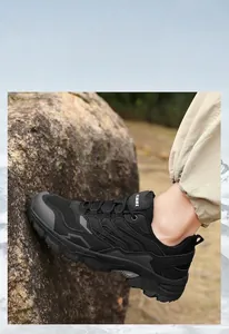 Black outdoor hiking shoes with deep groove rubber soles climbing on rocky terrain