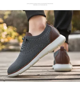 Nahaufnahme grauer Strick-Sneaker mit braunen Lederakzenten und dicker weißer Gummisohle