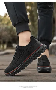 Detail of men's black mesh casual sneakers featuring red stripe accent on thick sole