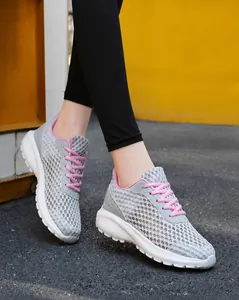 Dettaglio di scarpe da corsa in mesh grigio traspirante con lacci rosa indossate all'aperto