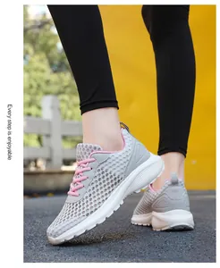 Vista laterale di scarpe da corsa in mesh grigio per donna con lacci rosa e suola spessa
